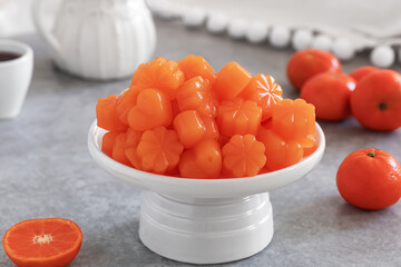 Homemade orange jelly candy on white serving stand. Real fruit juice jelly sweets made from fresh clementine or mandarin juice, sugar and agar agar powder. Selective focus, horizontal