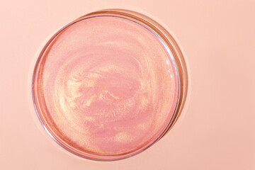 Liquid rose gold. Or a pink liquid with glitter. In a Petri dish. Laboratory research of cosmetics, gel, medicine. Chemistry