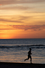silhouette of a person running on the beach at sunset