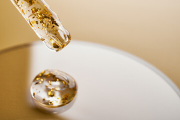 Pipette and gel cosmetic products with gold in a Petri dish on beige background