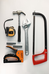 tools. on a light background, a set of an adjustable wrench for a hacksaw for metal, a tape measure hammer and a construction stapler