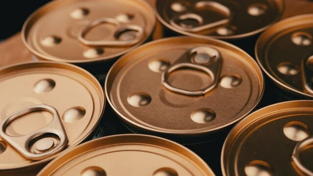 Close up, Slow Rotation of Metal Cans with Canned Food or Pate. Macro. Top view. Closed golden cans with pull rings. Canned tourist food or wet pet food, pate. Military, humanitarian aid to soldiers.