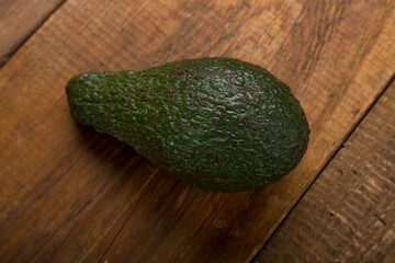 Fresh green avocado lies on a wooden table.