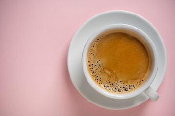 White porcelain coffee cup with saucer over pink background, top view, copy space, closeup. Hot...