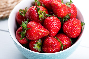 Fresh strawberries in a blue bowl on a table.  Fresh ripe delicious strawberries in a bowl. Close-up.  