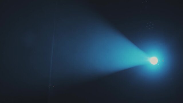 The blue light from the spotlights through the smoke in the theatre during the performance. Lighting equipment.