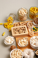 Nutritional supplements, organic minerals and many different vitamins such as vitamin a, d3, c, e, b in small glass jars and plates on wooden desk from above on light background in rustic style. 