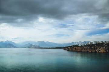 Obraz premium Mediterranean Sea with mountains and apartment buildings in the distance seen from Antalya coast, Turkey