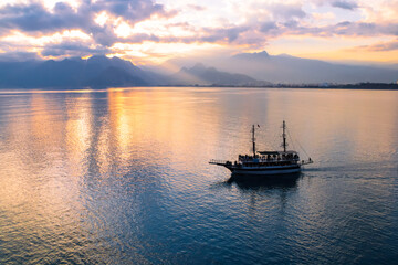 Fototapeta na wymiar Landscape of boat - yacht in the Mediterranean sea with mountains in the distance during the sunset, Antalya, Turkey