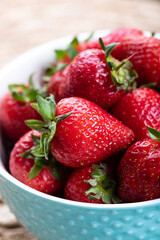Fresh strawberries in a blue bowl on a table.  Fresh ripe delicious strawberries in a bowl. Close-up.  