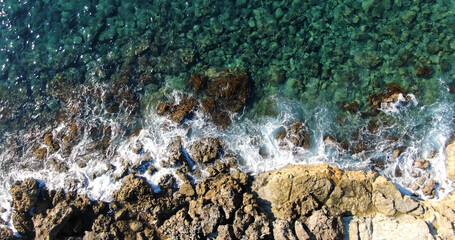Aerial top view rocky shore and foamy waves