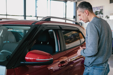 A man examines a car in the cabin for defects. Car rent. Buying a car