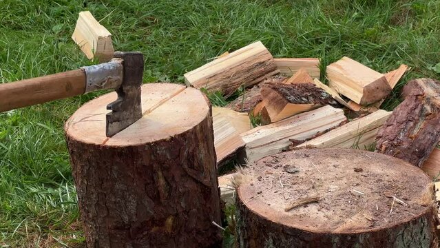 A man chopping wood with an axe in the village on a stump.