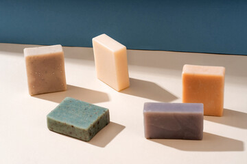 Pattern natural handmade soap of different sizes and colors. Brown background shadows of flowers from the sun. Cosmetic pedestal for product promotion.