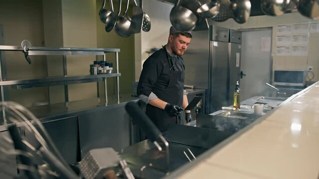 professional kitchen in a hotel restaurant the chef flips a burger patty with a spatula in the air