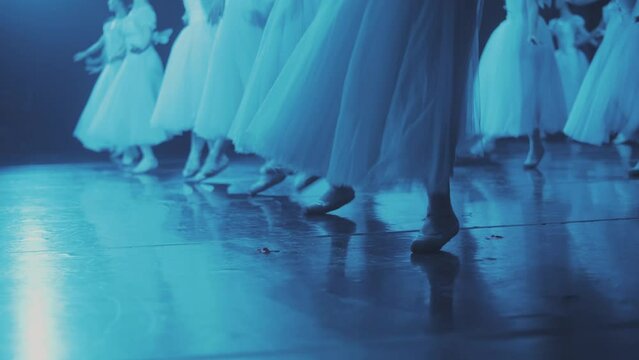 Synchronized dance of ballerinas in pointe shoes. on stage. a lot of pairs of legs in the frame. Synchronous leg movements ballerin.