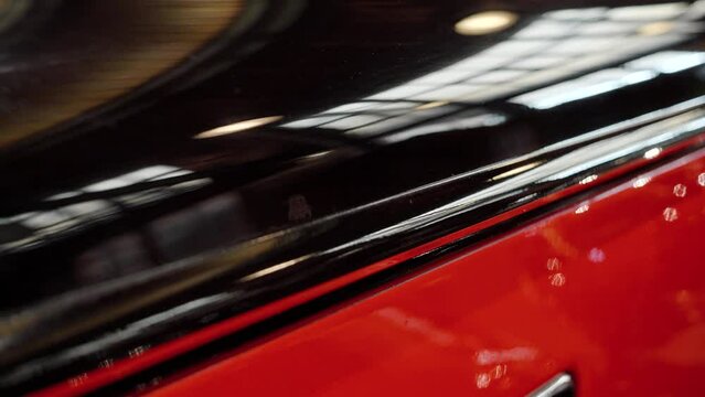Dolly shot of glossy polished surface of vintage car painted in black and red.