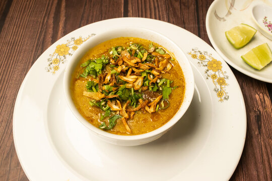 Chicken Haleem or halim daleem with fried onion served in dish isolated on wooden table top view indian spices food