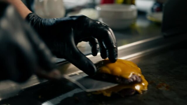 professional kitchen in hotel restaurant chef puts smash burger patty with cheese on burger buns prepares dish serving
