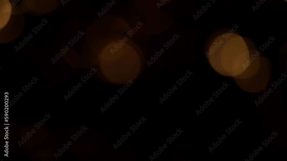 Wall mural slow movement of golden sepia bokeh on a black background. beautiful luminous overflow transition of