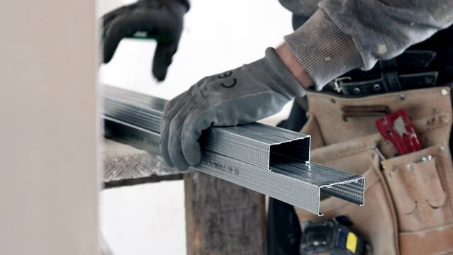 Construction worker cutting a guide for installing a plasterboard ceiling. Renovation, construction and do it yourself DIY concept