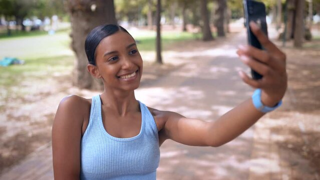 Selfie, fitness and happy woman in park for social media, workout goals and mobile app for training and peace sign. Indian sports person, influencer or runner in forest with workout profile picture