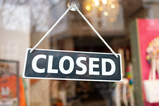 a "closed" sign is attached with a suction cup to the glass of the entrance door of a fashion boutique