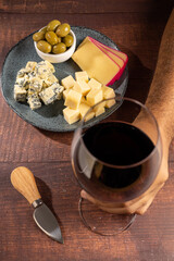 Plate of different cheeses with a glass of wine.