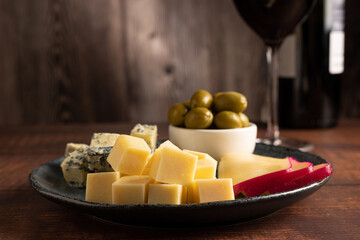 Plate of different cheeses with a glass of wine. Cheese board.
