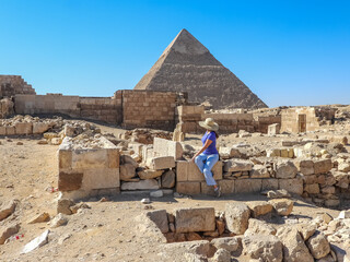  Girl dressed in blue with a hat, looking at the pyramid of Chephren in Cairo, Egypt.