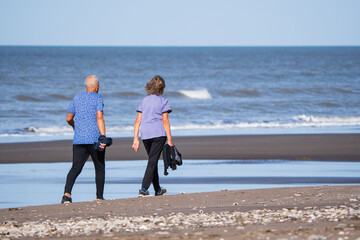 Elderly couple walking and exercising on a beach.