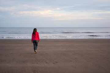 Obraz premium Woman walking on an Argentinian beach at sunset