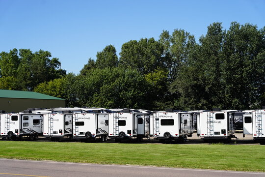 Different brand camper trailers sit in a parking lot for storage.