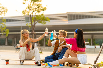 Asian man and woman friends resting together after skating on longboard skate at public park....