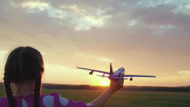 Child play toy airplane. Kid aviator dreams of flying and becoming pilot. Little girl child wants to become pilot and astronaut. Slow motion. Happy girl runs with toy airplane on field in sunset light