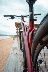Fototapeta na wymiar Bicicleta vermelha apoiada na madeira na beira da praia