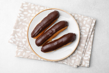 Delicious eclairs covered with chocolate on grey table, top view