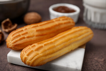Delicious eclairs and walnuts on grey table, closeup