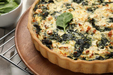 Delicious homemade spinach quiche on wooden board, closeup