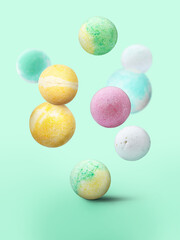 Many different bath bombs falling on pastel turquoise background