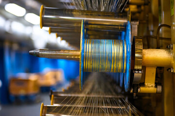 Thin cables coiled on creels and metal rollers in workshop - obrazy, fototapety, plakaty