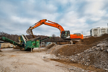 Excavator loads soil in mobile crushing and sorting complex