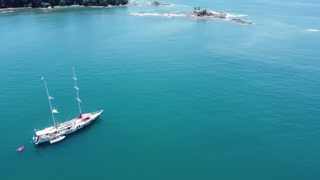 Bote en playa Dominicalito, Puntarenas Costa Rica, vista de drone rodeando bote con vista al  mar y a la costa desde arriba