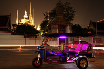 Tricycle in Bangkok city Thailand is known as a tuk tuk with the backdrop of the Wat Pho pagoda.