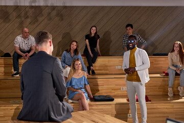 African black male student stands expressing opinion about marketing and management for successful sales indoors closeup. Professional ideas, politics. Rear View on man speaking in conference hall.