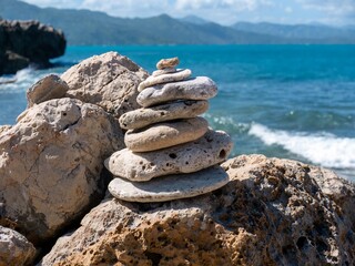 Stack of rocks with a tropical ocean and mountains in the background