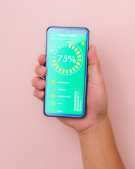 Male hand holding smart phone on pink background with smart home technology interface on smartphone app screen. Concept of automation.