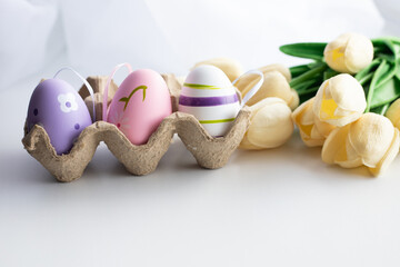 Easter eggs in a package with flowers and tassels on a white background