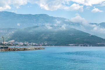 Budva Riviera in the morning, Montenegro. View from the Adriatic Sea to the city coastline and mountains in fog and clouds on the horizon