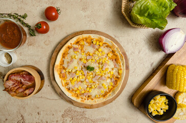 Top view closeup shot of delicious tasty juicy thin crispy cheesy corn and ham Italian pizza placed on wooden board on party table around with other ingredients, sauce, olive oil, bacon and tomatoes